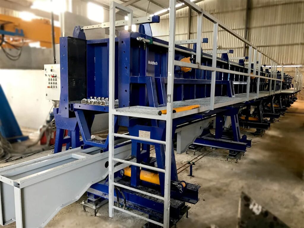 Blue precast concrete moulding machine in an industrial facility.