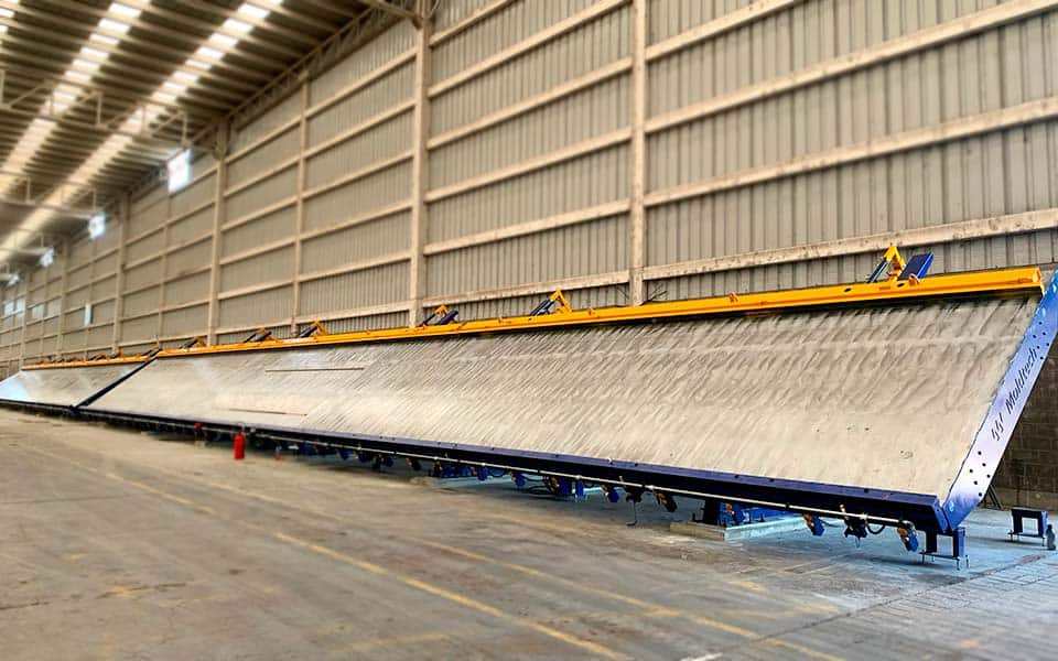 A large tilting table for precast concrete production inside a spacious industrial facility, showcasing its robust design and capacity for casting wide concrete panels.
